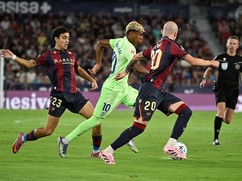 El delantero del Barcelona, ​​Lamine Yamal, lucha por el balón con el defensa del Levante, Manu Sánchez, y el centrocampista Oriol Rey, durante el partido de LaLiga en el estadio Ciutat de Valencia. Foto: EDH AFP