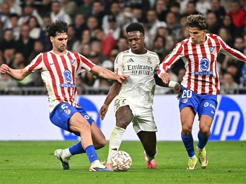 El centrocampista del Atlético de Madrid, Johnny Cardoso (i.), marca al delantero brasileño del Real Madrid, Vinícius Júnior, junto a su compañero argentino Giuliano Simeone, en partido de la liga española. Foto: EDH AFP