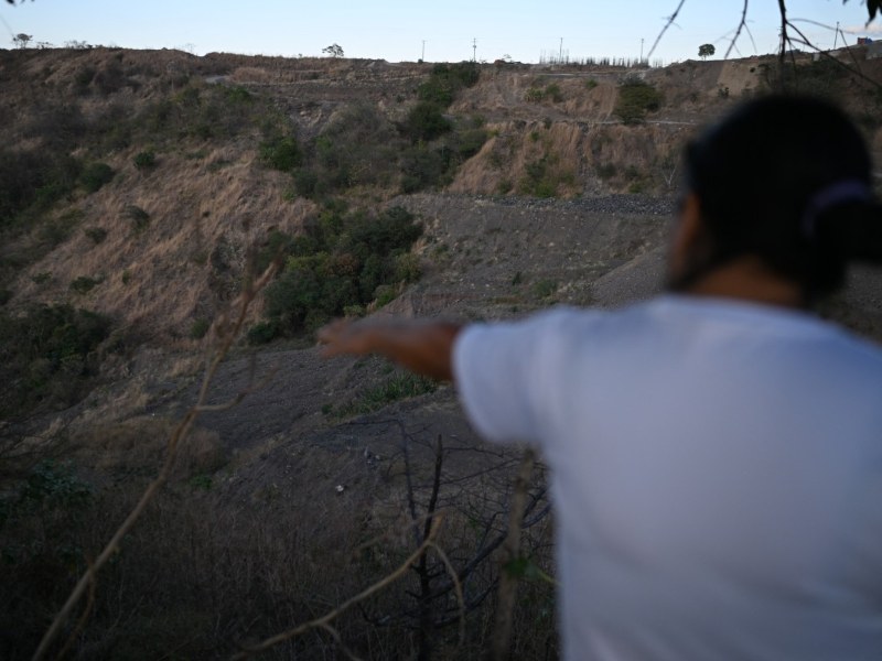 Tomasa López señala un profundo barranco en el barrio de Montreal, en Mejicanos, El Salvador, donde sospecha que podría estar ubicado un cementerio clandestino de víctimas de pandillas y donde podrían encontrarse los restos de su hija, desaparecida desde 2016. Foto EDH/AFP