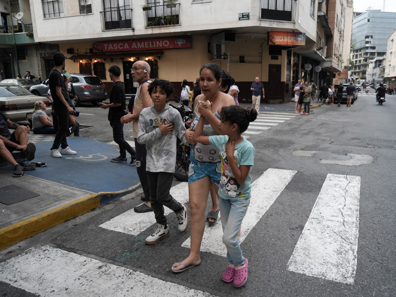 Grupo de personas reunidas en medio de una calle urbana en Caracas tras evacuar edificios debido a un sismo.