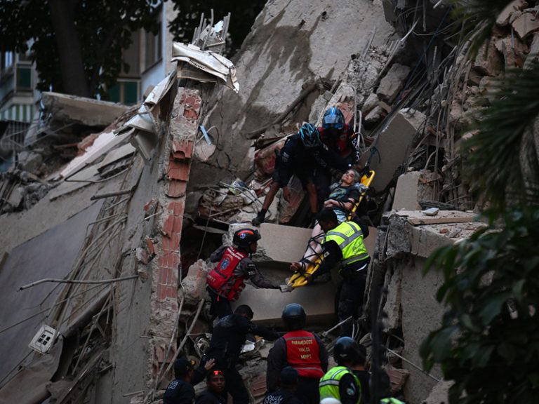 Miembros de los servicios de emergencia cargan con cuidado una camilla con un herido, evacuándolo a través de una zona cubierta de escombros de un edificio destruido en Caracas.