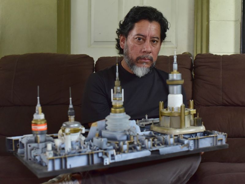 Artista visual Óscar Pérez mostrando parte de su instalación "De ciudadelas, urbanismo y distopías flotantes"