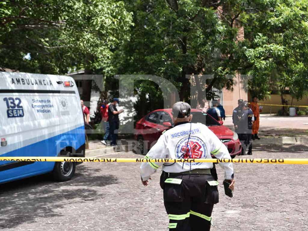 Una socorrista de espaldas con uniforme blanco y franjas reflectivas observa el patio del INFRAMEN acordonado con cinta amarilla, donde se ve un camión de bomberos y un grupo de personas al fondo.