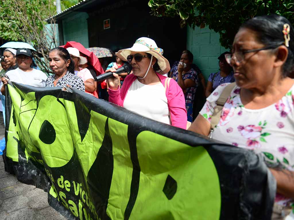 Mujeres miembros de MOVIR sostienen pancartas exigiendo juicios individuales justos y el fin de las condenas masivas.