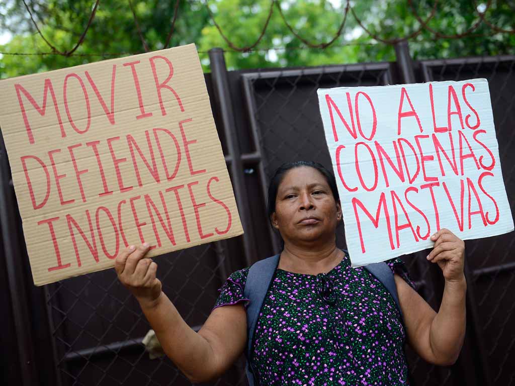 Manifestante sostiene carteles hechos a mano que dicen "MOVIR defiende inocentes" y "No a las condenas masivas".