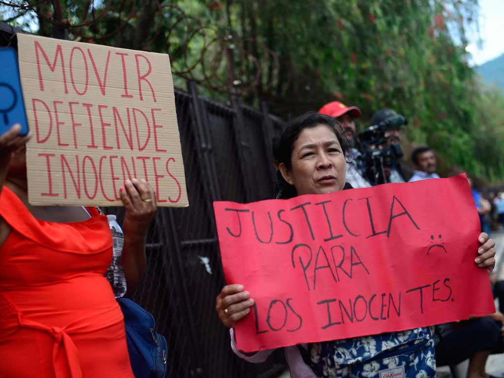 Una manifestante sostiene una cartulina roja que dice "Justicia para los inocentes" con un dibujo de una carita triste.
