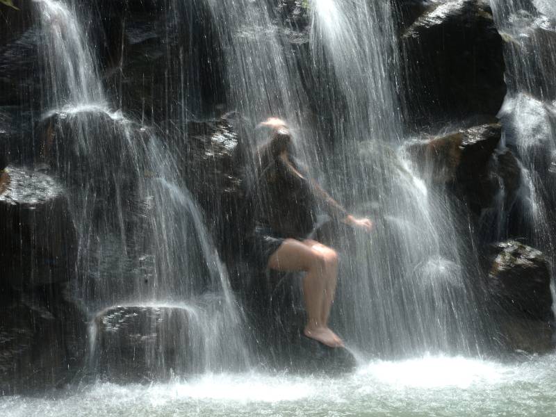 Turista disfruta de un baño relajante bajo las cascadas naturales en el turicentro Los Chorros, El Salvador