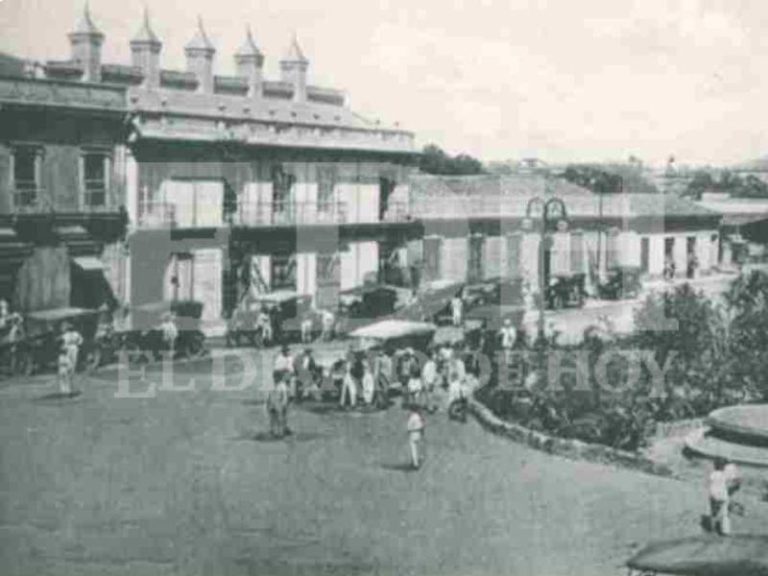 Vehículos de época frente a la Plaza Morazán, San Salvador. De fondo, el Banco Salvadoreño.
