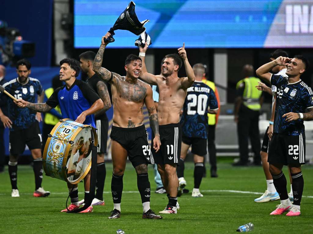 Lionel Messi y varios de sus compañeros, algunos de ellos sin camiseta como Nicolás González, corren y saltan sobre el terreno de juego celebrando con los brazos en alto ante la mirada de la tribuna repleta.