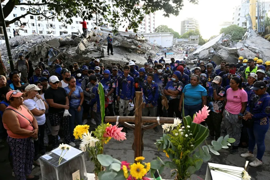 Frente a los escombros de los edificios de vivienda social conocidos como OPP, en Caraballeda, decenas de personas se pararon frente a un altar de flores y recuerdos de estos edificios y prendieron velas.