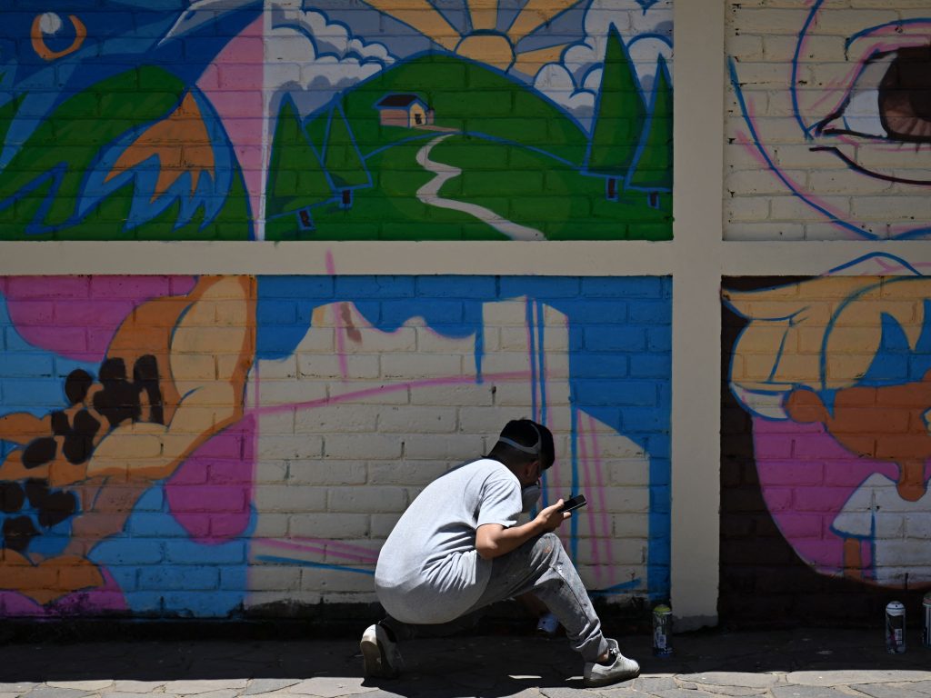 Muralista pinta un muro en Concepción de Ataco como parte de un certamen de muralismo