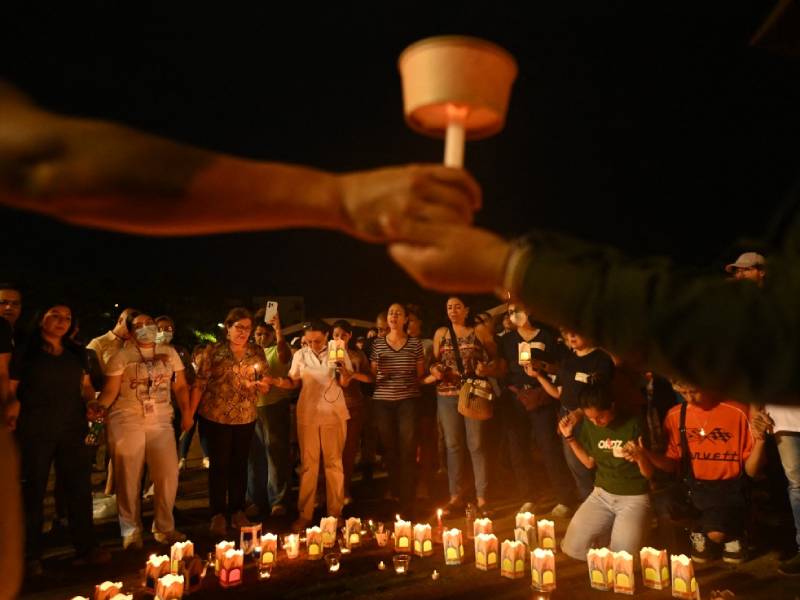 Personas reunidas de noche sosteniendo velas encendidas en una plaza de Cali en memoria de los fallecidos.