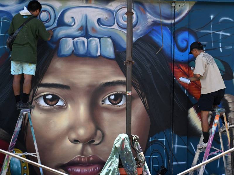 Varios artistas urbanos pintan murales coloridos en las calles de Concepción de Ataco durante un festival local.