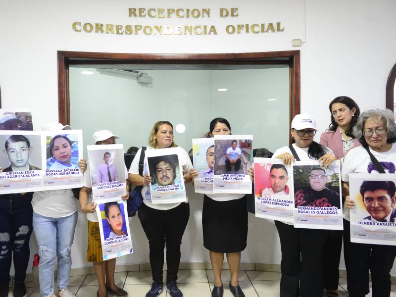 Personas sostienen retratos de sus familiares desaparecidos en un acto público exigiendo respuesta de las autoridades