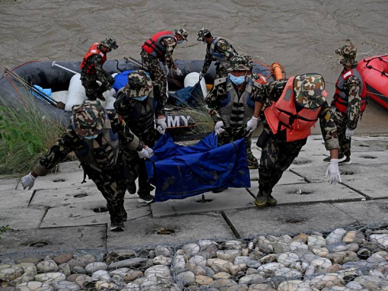 Personas cavan fosas e inician sepulturas masivas de víctimas rescatadas en un terreno terroso en Nepal.