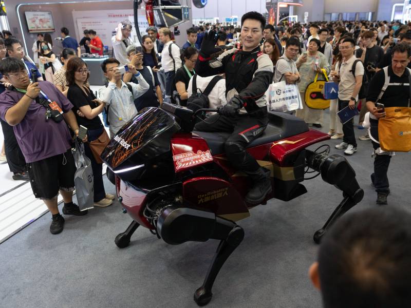 Hombre montado sobre un robot cuadrúpedo en la Conferencia Mundial de Robótica en Pekín.