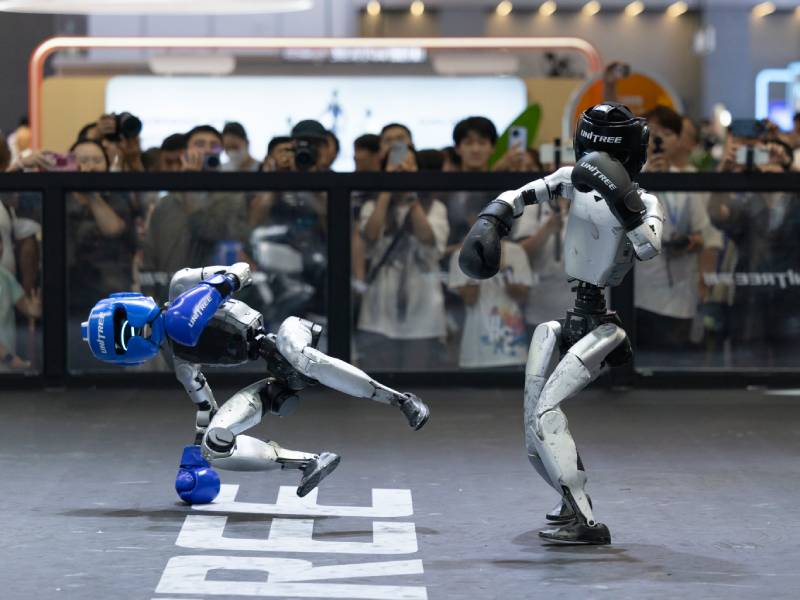 Dos robots humanoides de la empresa Unitree simulando una lucha en su pabellón de la Conferencia.