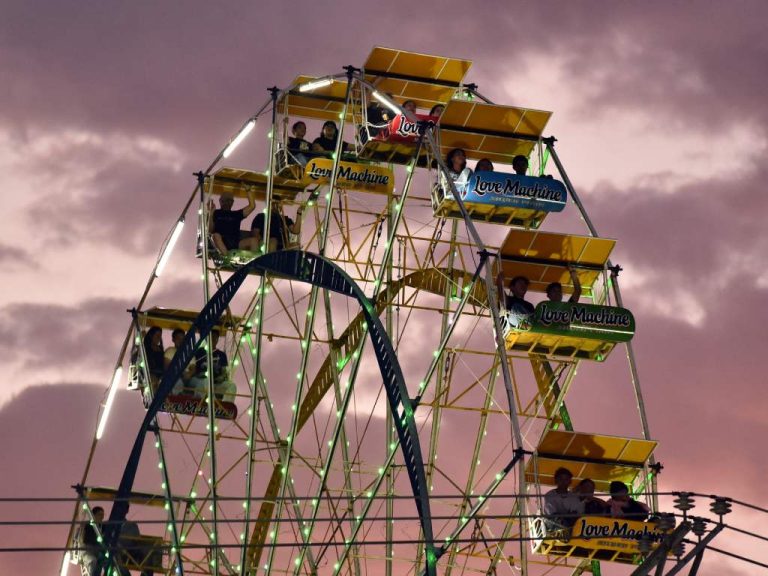 La rueda de la fortuna de la feria Sivarland brilla suavemente con luces de neón en los primeros minutos de la noche, ofreciendo vistas panorámicas a sus pasajeros.