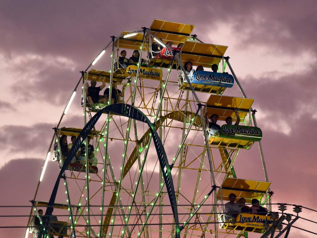 La rueda de la fortuna de la feria Sivarland brilla suavemente con luces de neón en los primeros minutos de la noche, ofreciendo vistas panorámicas a sus pasajeros.
