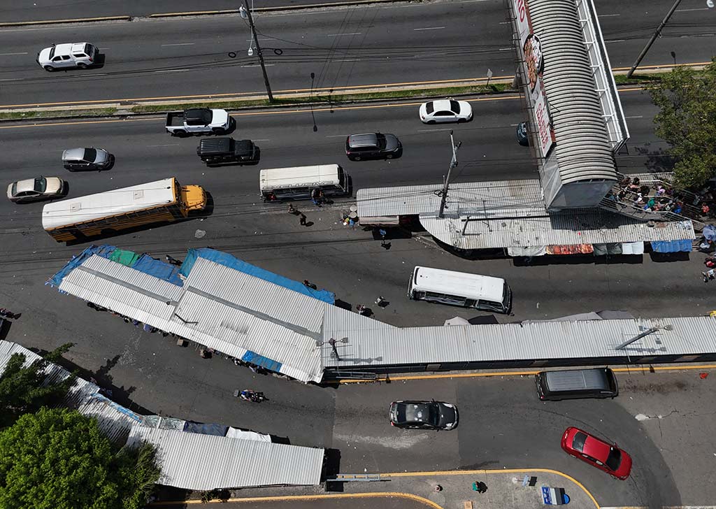 Imagen de dron que muestra una calle estrecha en Soyapango flanqueada por numerosos puestos de venta con techos de lámina. Se aprecian árboles frondosos y techos de zinc de edificios aledaños. Es una vista cenital que captura la densidad del comercio informal.