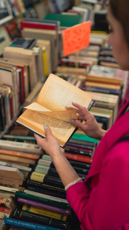 Joven lee un libro en una venta de títulos en físico