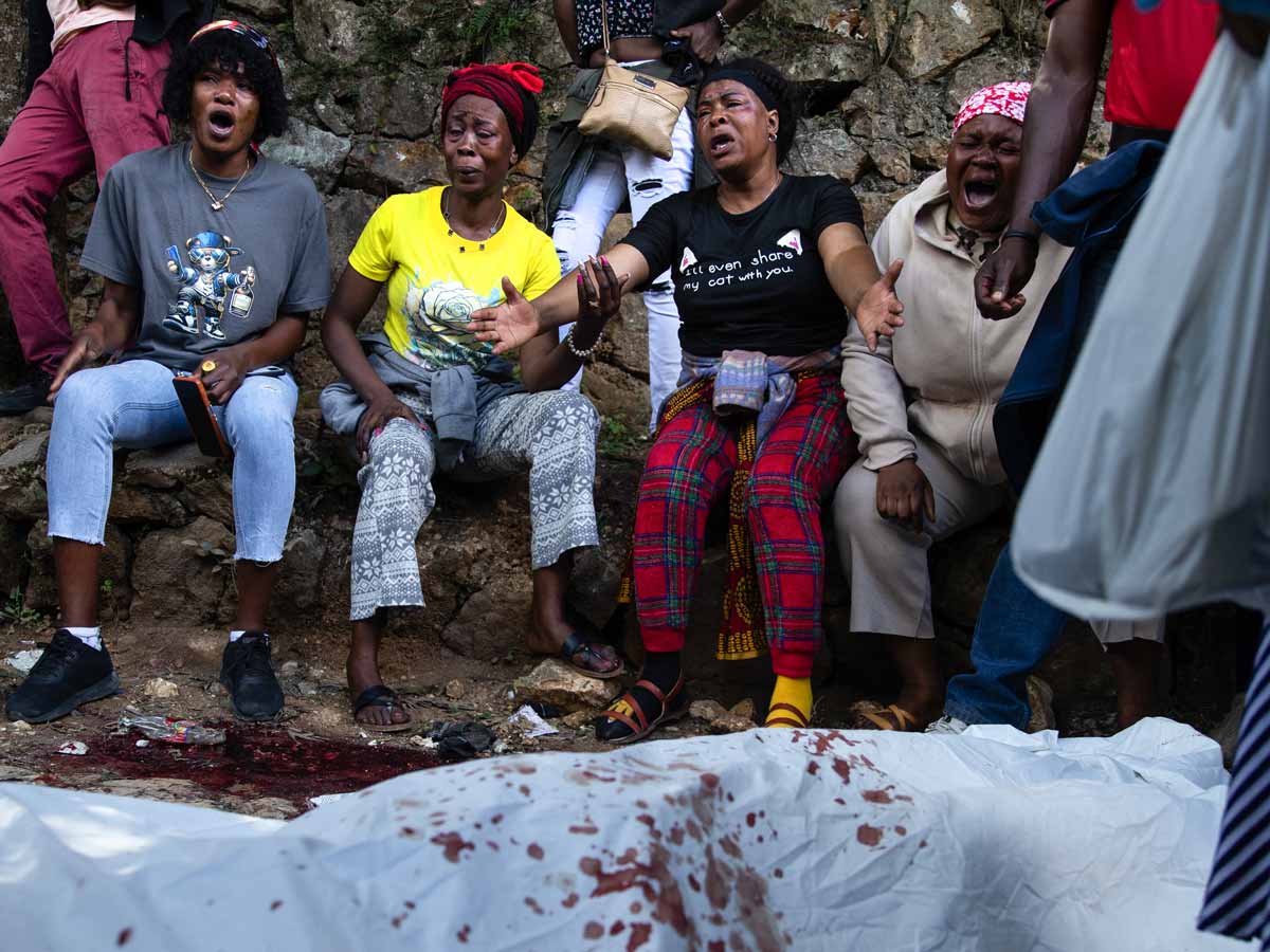 Mujeres haitianas llorando desconsoladamente junto al cuerpo cubierto de una víctima de la violencia.