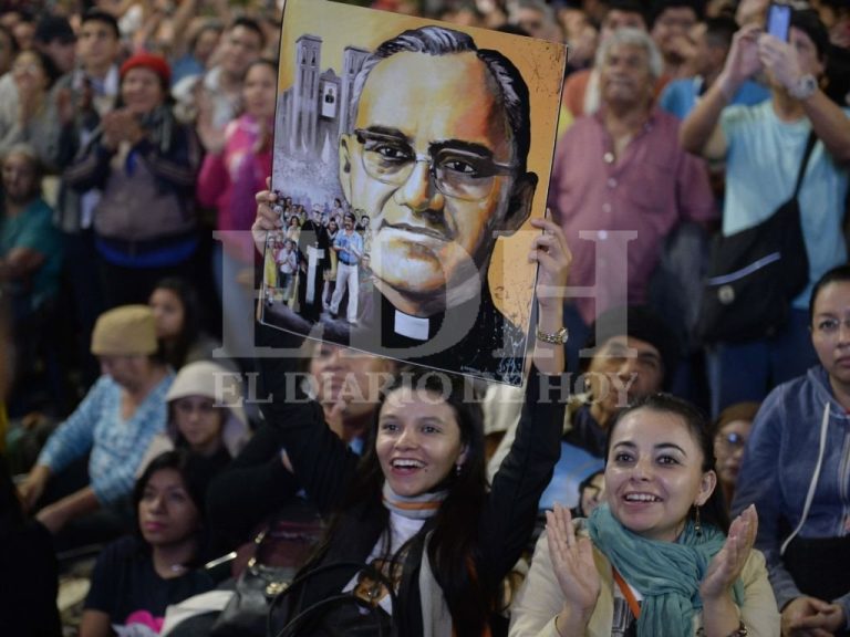Fieles expresan su alegría y aplauden sosteniendo una pintura con el rostro de San Óscar Romero.