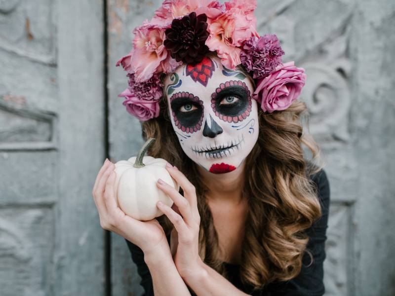 Catrina sosteniendo en sus manos una pequeña calabaza