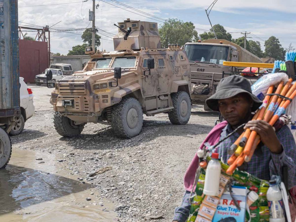 Vendedor de artículos para el hogar en Puerto Príncipe frente a un blindado de combate de las tropas aliadas de la ONU